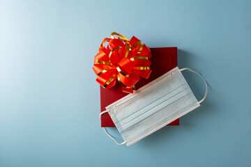 Red gift box with bow and face mask, healthy holiday concept
