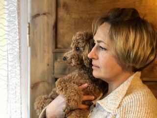 a woman holding a puppy in her hands and looking out the window