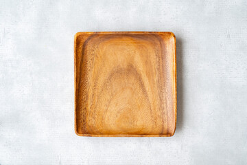 グレーの背景に置かれた木製で四角形の皿