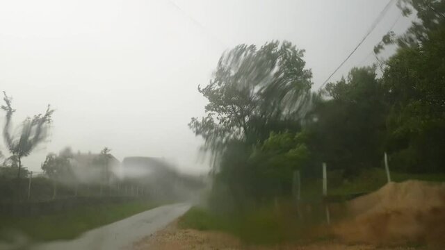 Storm rain falls on the asphalt road, shot through car window - (4K)