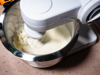 cooking sweet sponge cake at home - above view of stirring of liquid cream with sugar in steel bowl...