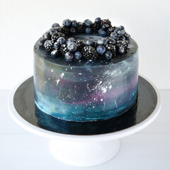 Cake with the image of the cosmos drawn by airbrush decorated blueberries, blackberry. Galaxy, stars in the night sky. Cutout.
