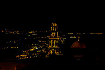 Fototapeta na wymiar Rooftops and church towers illuminated at night in Thira, Santorini in summertime