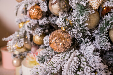 Christmas tree decorated with toys in gold and pink color. Christmas ornaments,ribbons, stick figure deer, beads and lights glowing garland. Winter Holiday.Luxury new year decor.