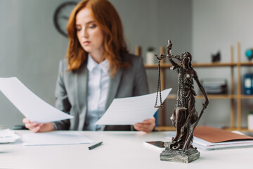  figurine on table with blurred lawyer with paper sheets on background