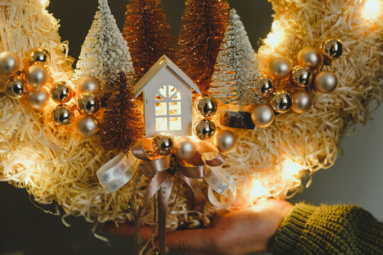 Closeup Handmade Christmas Wreath with Lights in Woman Hands for Winter holidays tradition, Lght garland, Natural and Ecofriendly Materials