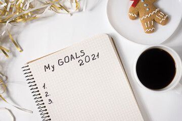 Phrase My Goals 2021 in a notebook. Mug of coffee, gingerbread man and tinsel. Close up