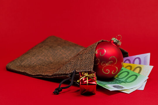 Geldscheine, Weihnachtsgeld im Jutebeutel vor rotem Hintergrund