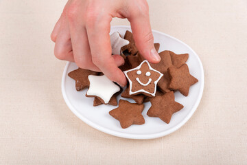 Female hand holds a gingerbread cookie in shape of star emoticon. Glazed painted cookies