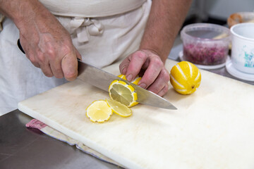 Chef cuisinier qui coupe des citrons sur une planche à découper avec un couteau