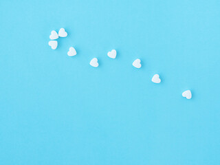 Pharmaceutical and cardiology concept. White medical cardiological pills in the form of heart on blue background. Minimalism style template for medical blog. Cope space for text. Pills of love