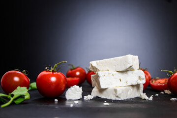 Feta cheese with tomatoes on black background