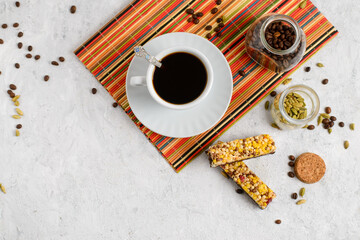 Top view of coffee with spices in a white Cup and a granola bar on a colored stand on a light...