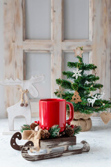 Red mug on a sleigh. Christmas tree by the window. Christmas concept.