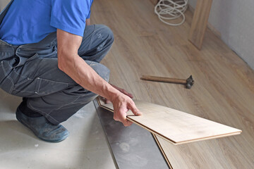 Working carpenter lays laminate flooring in the apartment. The concept of working professions.