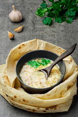 Traditional hot khash soup in a bowl, top view. Traditional Armenian, Turkish or Caucasian oriental dish - khash, with fresh cilantro, garlic and dried lavash bread