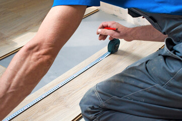 Working carpenter lays laminate flooring in the apartment. The concept of working professions.
