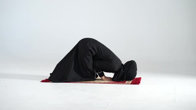Asian muslim woman in black dress wearing HIJAB doing daily islamic pray on white background. 