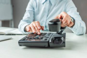 Fototapeta premium Cropped view of businesswoman with handset dialing number on landline telephone at table on blurred 