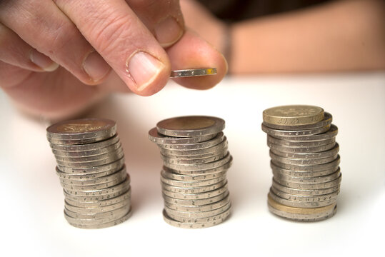 Closeup of hand of woman stacking euro coins on a white table