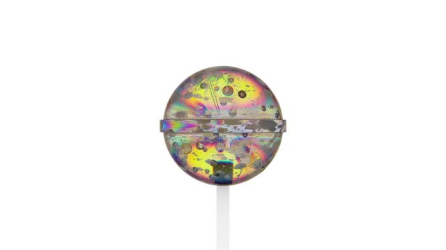 Transparent rainbow caramel on a stick rotates quickly counterclockwise on a white background.