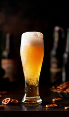 Beer in a glass glass, the foam flows down the glass. Beer publ. Beer snack - salty pretzels