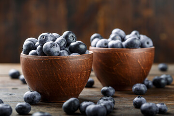 Fresh blueberries in a clay bowl and scattered on a wooden table. Foods containing antioxidants.