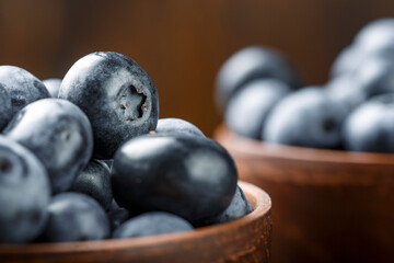 Fresh blueberries in a clay bowl and scattered on a wooden table. Foods containing antioxidants.