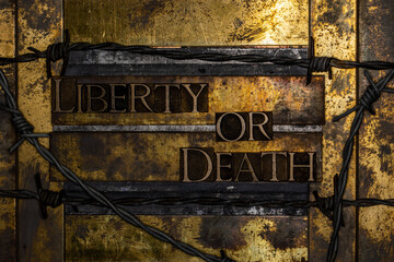 Liberty Or Death text with barbed wire on textured grunge copper and vintage gold background 