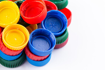 Many multi-colored plastic bottle caps on a white background.