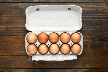 Chicken eggs in a tray on a wooden table.