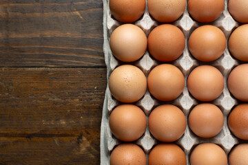 Chicken eggs in a tray on a wooden table.