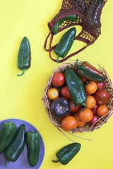 Ripe tomatoes and peppers, basket with organic fresh vegetables on the table for making healthy homemade food, top view