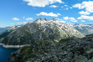 Obraz premium Dam in Austrian Alps. The artificial lake stretches over a vast territory, shining with navy blue color. The dam is surrounded by high mountains. In the back there is a glacier. Controlling the nature