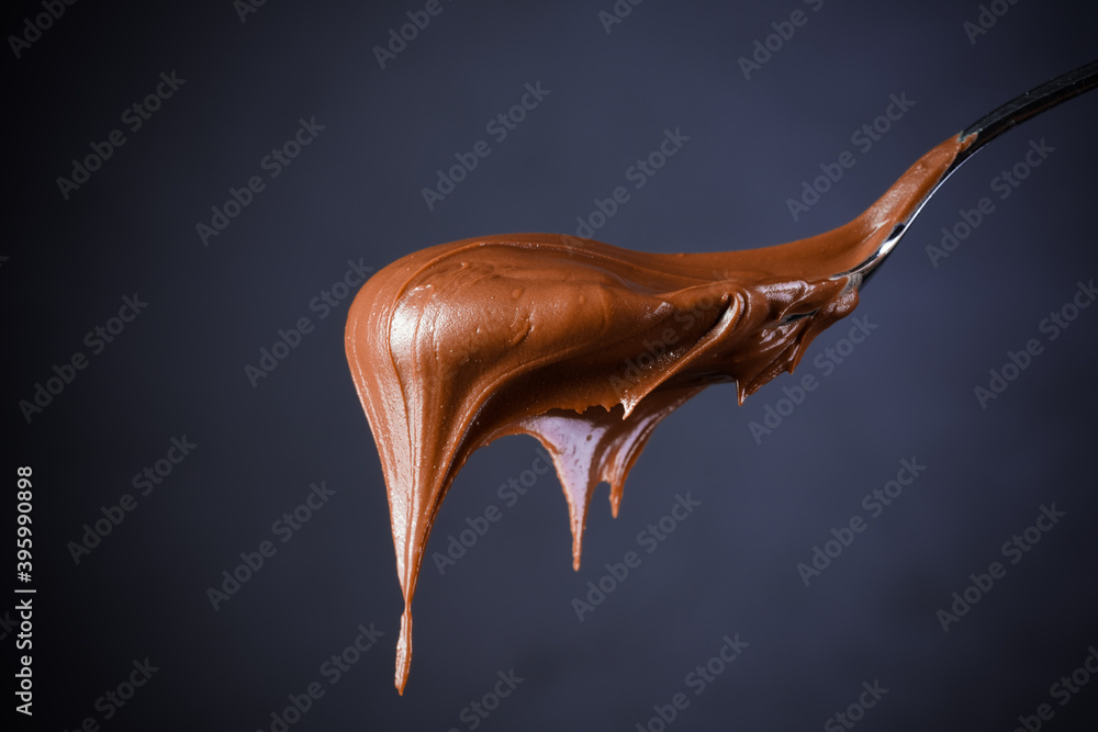 Wall mural Cream chocolate in spoon on black background