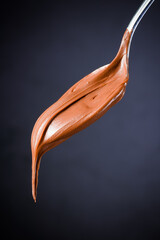 Cream chocolate in spoon on black background