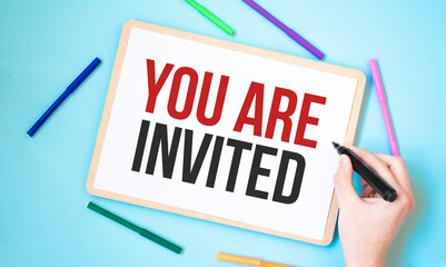 Text You Are Invited on a notebook surrounded by colored felt-tip pens, business concept idea,