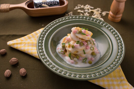 Egg noodles with cream, ham, peas and parmesan. Noodles with small pieces of ham and green peas, with Parmesan cheese and nutmeg.