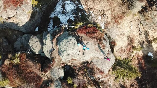 A top down capture of a couple standing at the top of a rock formation in Alps. Early spring in Alps. The nature wakes up after hibernation. Steep and dangerous climbing. Adventure
