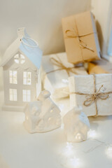 Christmas composition in light colors. White houses, gifts in white packages and festive lights. The concept of Christmas and New Year holidays. Vertical image.