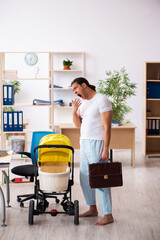 Young male employee looking after newborn at workplace