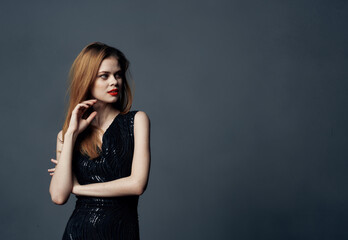 Fototapeta premium Beautiful woman in black dress red hair gray background Copy Space Model