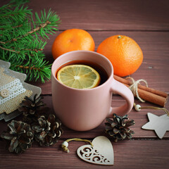 Fragrant tea, fir branches and tangerines on a wooden background.Happy winter holidays.