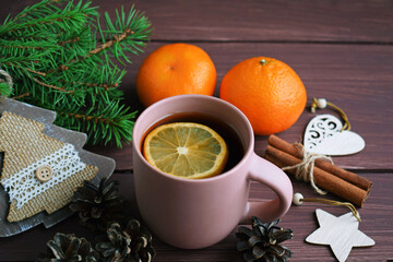 Fragrant tea, fir branches and tangerines on a wooden background.Happy winter holidays.