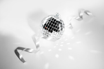 New Year's disco ball on a light background with highlights and ribbon. Christmas Holidays.