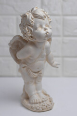 Fototapeta premium White plaster figurine of an angel on a brick wall background. Decorations in the interior.