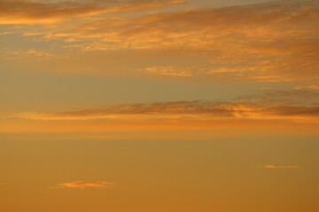 Sun below the horizon and clouds in the fiery dramatic orange sky at sunset or dawn backlit by the sun. Place for text and design