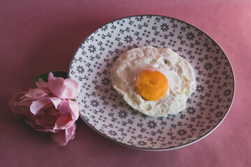 Homemade meal, Organic tasty cooked eggs for healthy breakfast on pink background, fancy ceramic plates, and flowers in a vintage artistic composition. Simple food composition