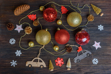 Christmas decorations, cones and children's cars on a dark wooden background. New year's card, top view.