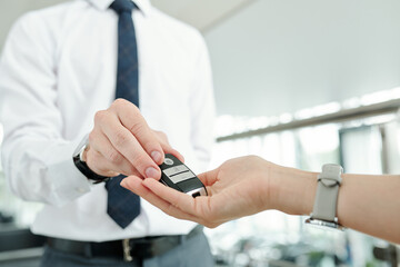 Hand of female taking remote control alarm system of car being passed by manager